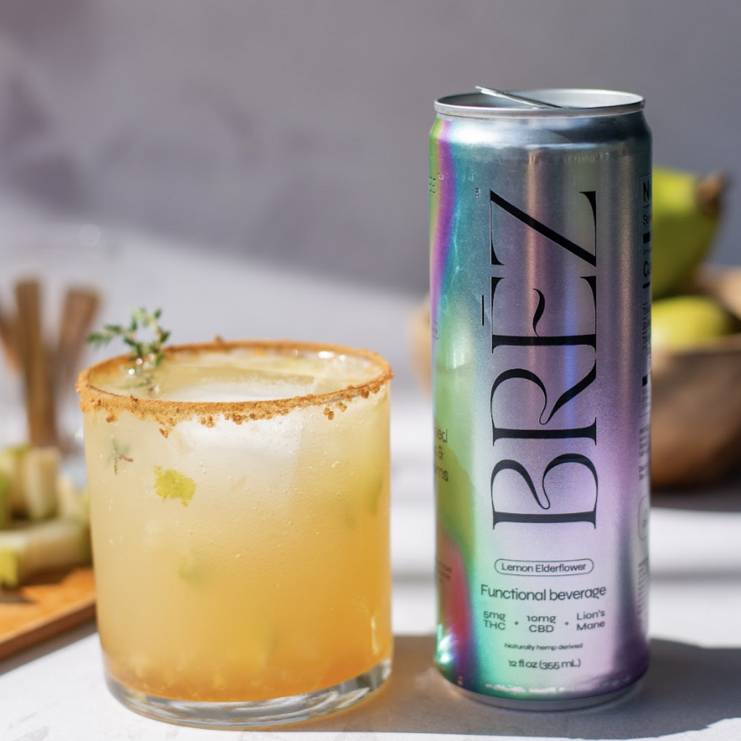 BREZ can next to a glass of a yellowish beverage with a cinnamon rim on a blurred background.